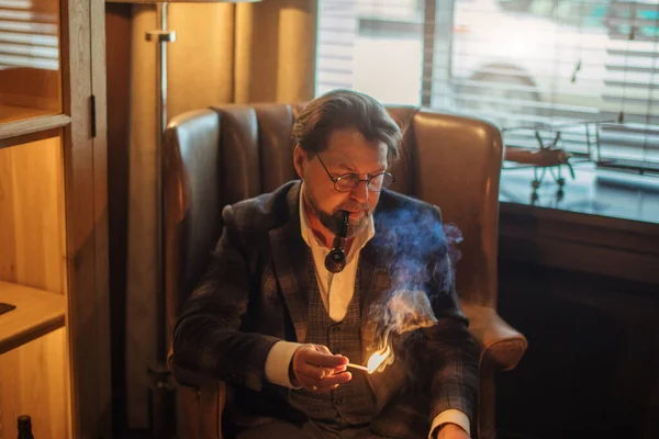 Креативний редактор, який обмірковує нову статтю, сидить з ноутбуком, курить трубу — стокове фото