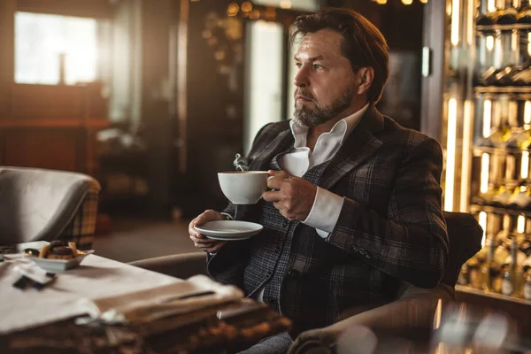 Pensativo hombre de negocios de mediana edad bebiendo café y mirando hacia otro lado en el restaurante —  Fotos de Stock