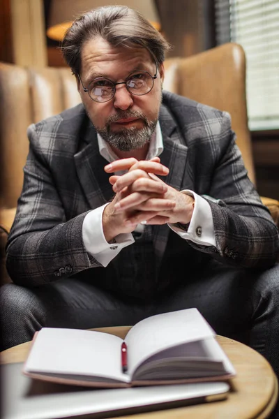 Hombre de negocios de mediana edad se sienta a la mesa y piensa en sus notas en el bloc de notas en la oficina — Foto de Stock