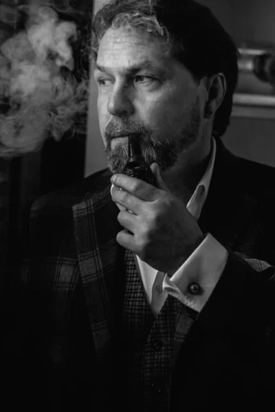 Reflexní dobře oblečený zralý vousatý muž v brýlích kouření tabákové dýmky — Stock fotografie