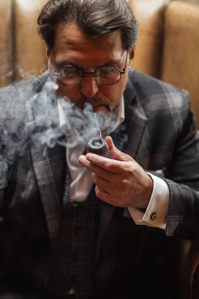 Riflettente uomo barbuto maturo ben vestito in occhiali da fumo tabacco pipa — Foto Stock