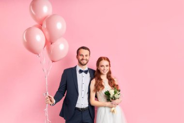 Pembe arka planda soyutlanmış güzel genç bir çiftin portresi.