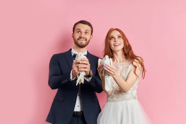 Νεαρό ζευγάρι που φοράει νυφικό και σμόκιν κρατά περιστέρια στα χέρια — Φωτογραφία Αρχείου