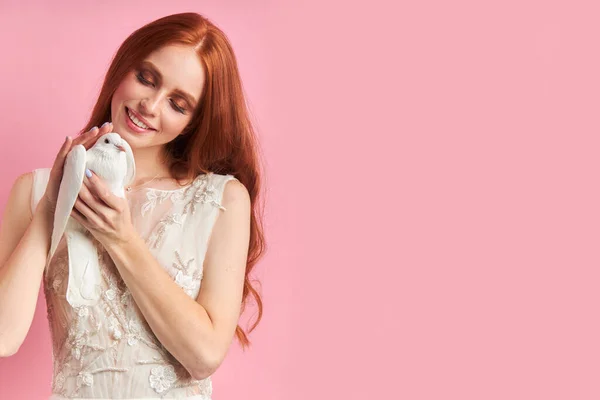 Mosolygó aranyos nő gazdaság fehér galamb és nézd szeretettel — Stock Fotó