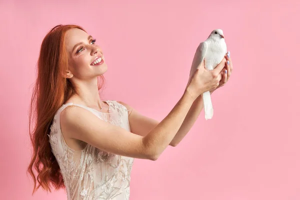 Smiling cute female holding white dove and look with love — Stock Photo, Image