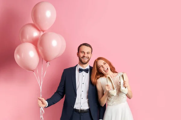 Casal feliz com balões de ar rosa isolado sobre fundo rosa — Fotografia de Stock
