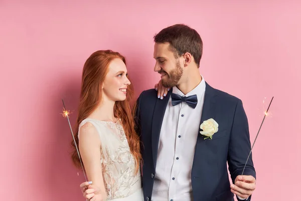 Linda pareja con fuego de bengala o bengala sobre fondo rosa — Foto de Stock