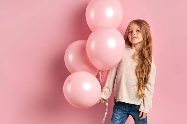 Portret van vrolijk meisje over roze achtergrond, met een bos van roze luchtballonnen — Stockfoto