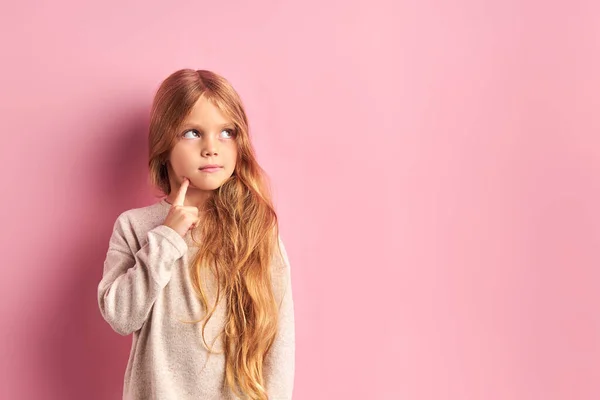 Споглядальна маленька дівчинка мріє ізольовано на рожевому фоні — стокове фото