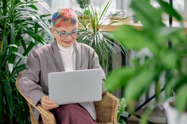 Gülümseyen başarılı iş kadını dizüstü bilgisayarla oturuyor.