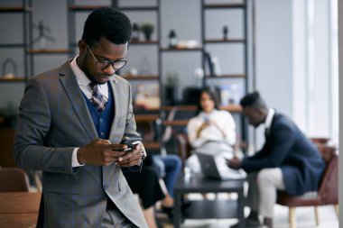 Meşgul genç Afrikalı adam iş sırasında cep telefonu kullanıyor.