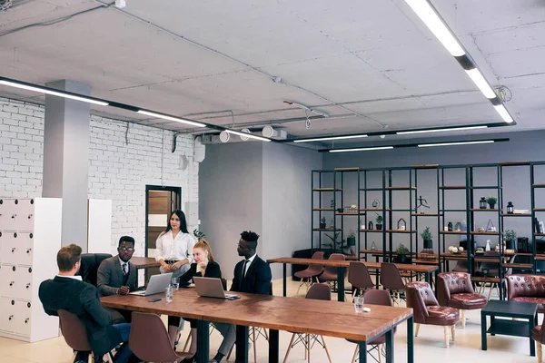 Mladí Afričané a běloši sedí v moderní kanceláři a vedou konverzaci — Stock fotografie