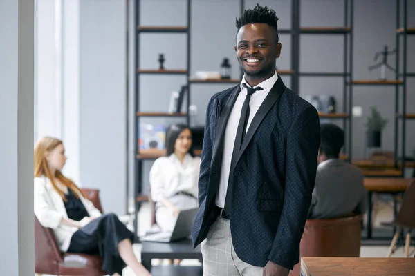 Porträtt av framgångsrik och leende ung afrikansk affärsman leder sitt team — Stockfoto