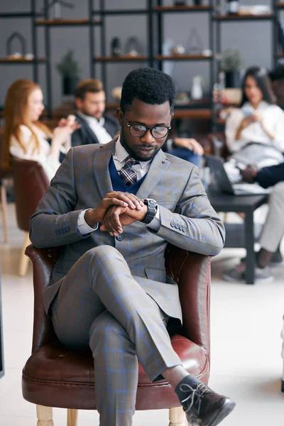 Portret van drukke Afro-Amerikaanse zakenman met blanke leidinggevenden die op de achtergrond werken — Stockfoto