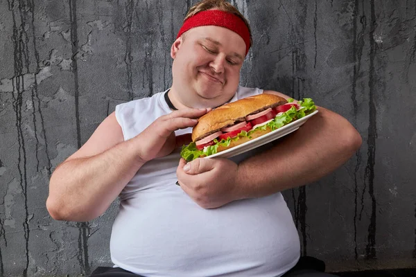 Szczęśliwy otyły facet głaskanie kanapkę, traktuje jedzenie z ostrożnością — Zdjęcie stockowe