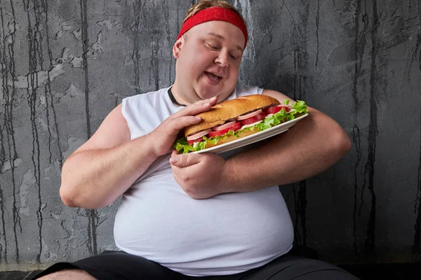 Szczęśliwy otyły facet głaskanie kanapkę, traktuje jedzenie z ostrożnością — Zdjęcie stockowe