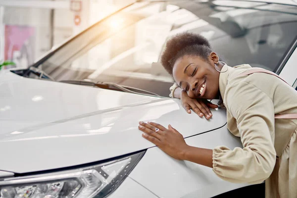 Sorridente signora nera abbraccia la sua nuova auto — Foto Stock