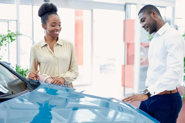 Black couple in contemplation before making purchase in cars showroom — Stock Photo, Image