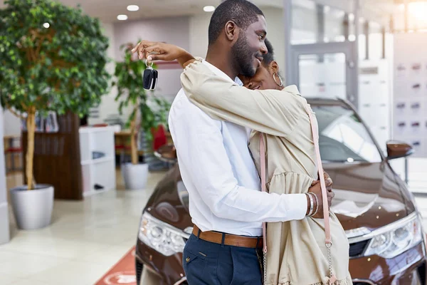 Retrato de bonito casado casal abraçando uns aos outros no carro showroom — Fotografia de Stock