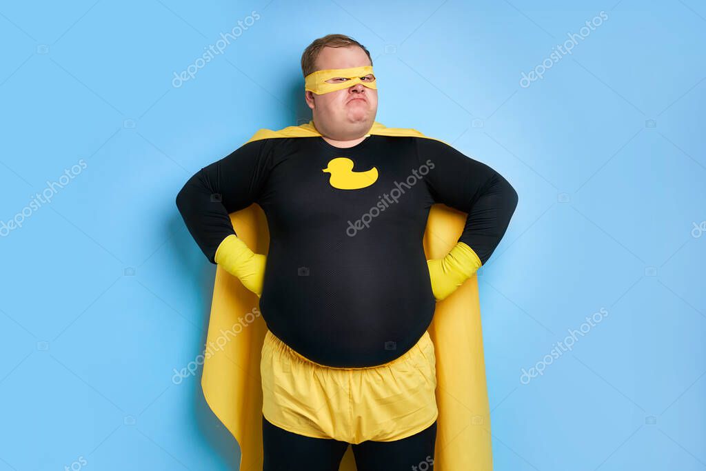 Portrait of enthusiastic cleaning superhero isolated over blue background. yellow duck is a symbol of bathing and cleaning. man is ready to clean
