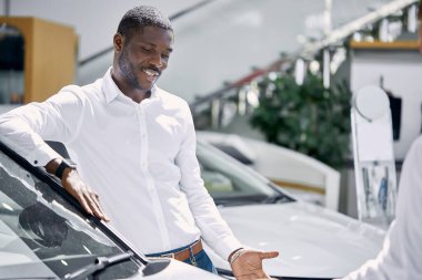 Esmer tenli müşteriler ve kendine güvenen yönetici veya danışman araba galerisinde konuşuyorlar.