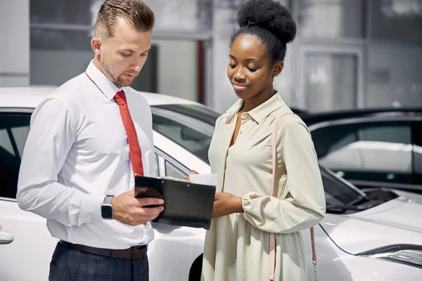 Confident caucasian salesperson selling cars at car dealership — Stock Photo, Image