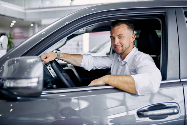 Schöner kaukasischer Kerl sitzt am Steuer eines neuen Automobils — Stockfoto