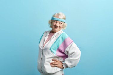 İyimser yaşlı kadın antrenör spor takımı ve saç bandı giyip izole edilmiş.