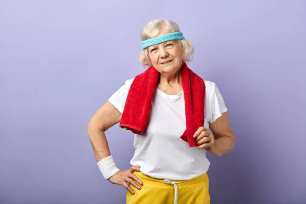 Пожилая спортсменка с повязкой и красным полотенцем на шее, смотрящая в камеру — стоковое фото