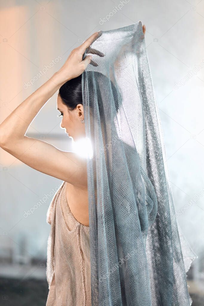beautiful ballerina wearing cape on head in stage grey loose transparent dress
