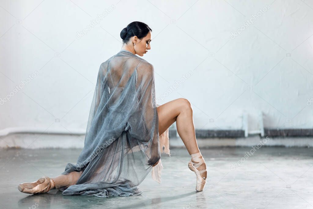 Modern style ballet dancer ex on a studio grey background in fog