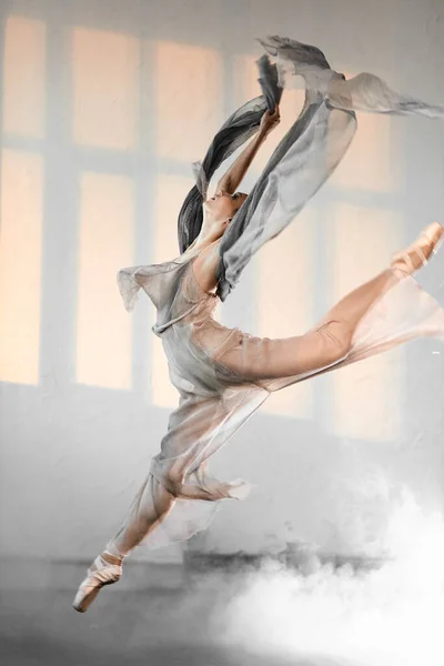 Joven bailarina de ballet saltando sobre un fondo ahumado . — Foto de Stock