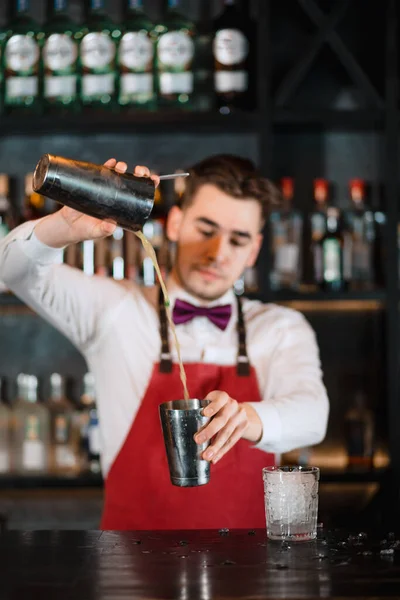 Barmen barın üstündeki bardağa taze kokteyl döküyor. — Stok fotoğraf