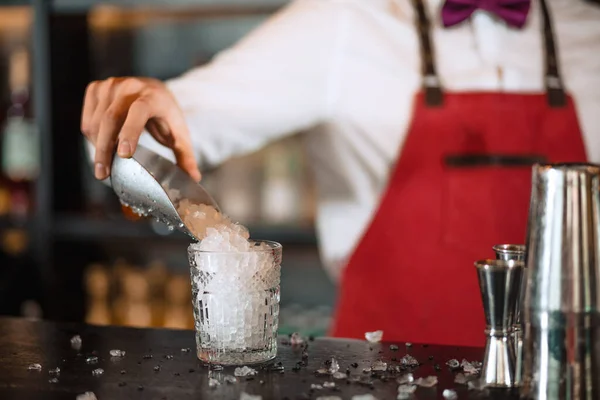 stock image Bartender in the white shirt adding ice into cocktail glass on the bar counter