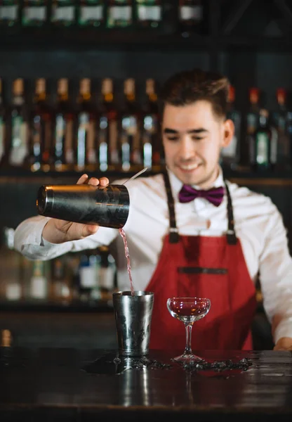 Barman vertiendo cóctel fresco de agitador en el vaso en el mostrador del bar —  Fotos de Stock