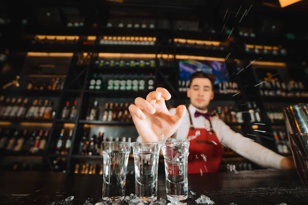 Руки бармена наливают напиток в рюмки на деревянный столик — стоковое фото