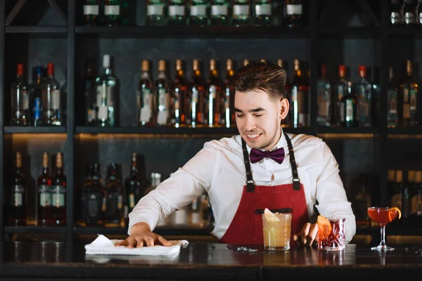 Portrét přátelského usmívajícího se pohledného mladého barmana stojícího u baru — Stock fotografie