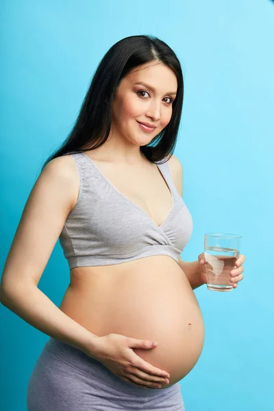 Tineri femeie însărcinată dezbrăcată cu burtă mare care ține un pahar de apă — Fotografie, imagine de stoc