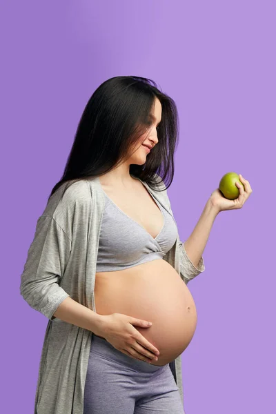 Plan isolé de la future jeune mère mangeant des aliments sains sur fond bleu — Photo