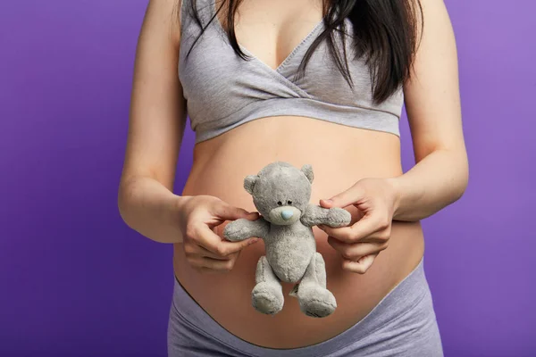 Mujer embarazada sosteniendo juguete osito de peluche, cerca de su gran vientre, de cerca — Foto de Stock