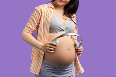 Kulaklık takan hamile bir kadın doğmamış bebeğinin klasik müzik dinlemesine izin veriyor..