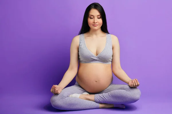 Mujer embarazada medita en interior en pose de yoga. Mujer disfrutando en meditación . — Foto de Stock