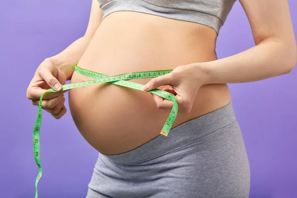Mujer embarazada midiendo el estómago con cinta métrica —  Fotos de Stock
