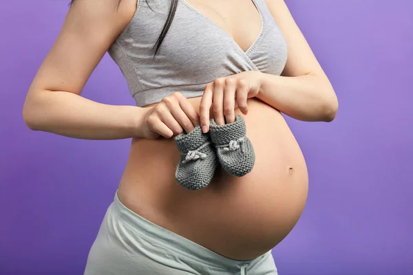 Botines de bebé para el feto en el vientre de la mujer embarazada —  Fotos de Stock