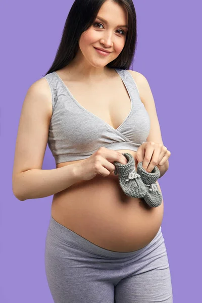 Obuwie dziecięce dla nienarodzonego dziecka na brzuchu kobiety w ciąży — Zdjęcie stockowe