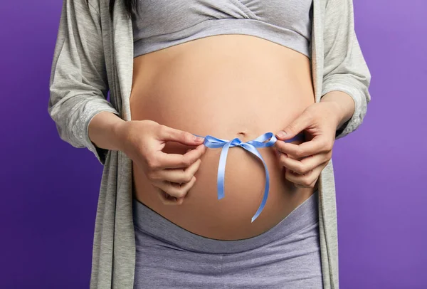 Vágott kép gyönyörű terhes nő átöleli a pocakját kék szalaggal — Stock Fotó
