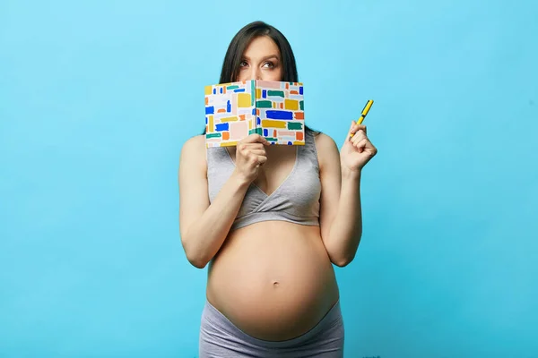 Femeia gravidă care face o listă de lucruri de ambalare pentru spitalul de maternitate, izolată — Fotografie, imagine de stoc
