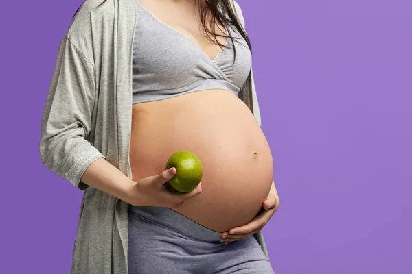 Foto aislada de futura madre joven comiendo alimentos saludables sobre fondo azul — Foto de Stock