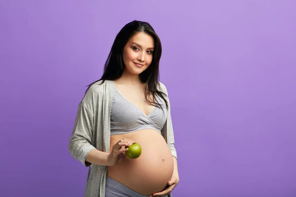 Foto aislada de futura madre joven comiendo alimentos saludables sobre fondo azul — Foto de Stock