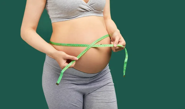 Mujer embarazada midiendo el estómago con cinta métrica —  Fotos de Stock